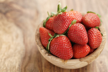 fresh strawberries in bowl on wood table, organic garden berries