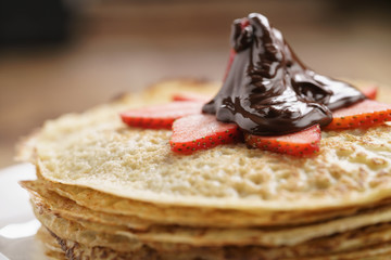 premium dark chocolate poured on blinis with strawberry, shallow focus