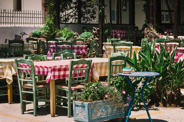 Fototapeta na wymiar Wooden table with green chairs at traditional Greek cafe