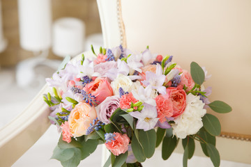 gentle bridal bouquet from pink peonies and white roses on a vintage sofa in a classical interior