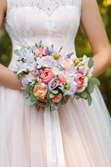 caucasian woman in beige wedding dress hold a bouquet of pink and purple flowers with peony