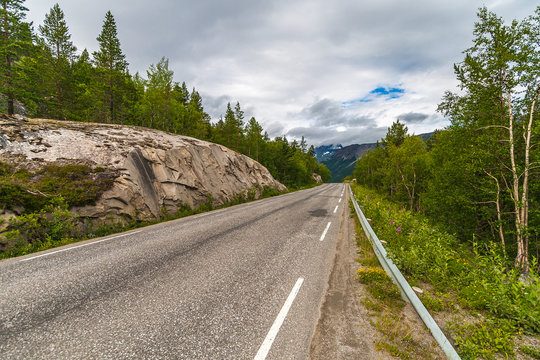 Country road among mountains and trees in Nordland county, Norway.