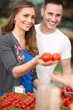 Couple buying organic vegetables at market.
