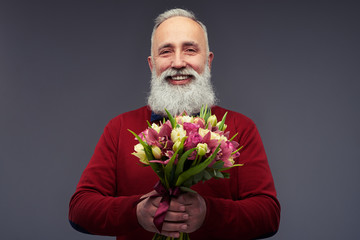 Handsome mature man with gray beard holding bouquet of flowers