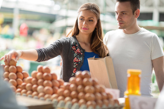 Couple buying fresh eggs at farmer’s market.