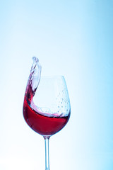 Bordeaux wine in the glass on a blue background. The concept of beverages and alcohol.