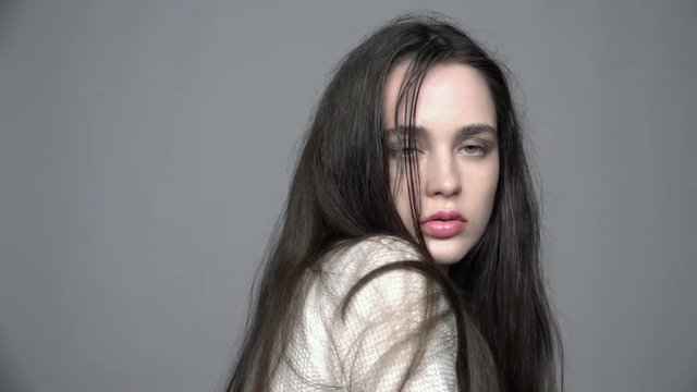 Slow motion video portrait of beauty young brunette woman portrait in white fashion female pullover