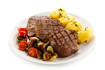 Grilled steaks, boiled potatoes and vegetable salad on white background 