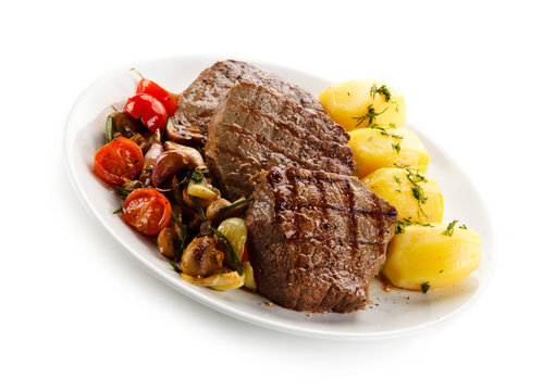 Grilled steaks, boiled potatoes and vegetable salad on white background 