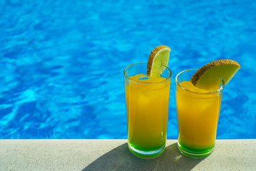Glasses with cocktail in front of a swimming pool with clear water