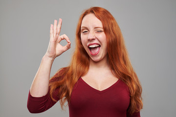 Fototapeta premium Exhilarated woman making ok gesture and winking