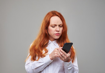 Confused girl looking attentively at the screen of mobile telephone