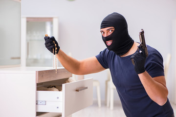 Robber wearing balaclava stealing valuable things