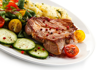 Grilled steaks, mashed potatoes and vegetable salad on white background