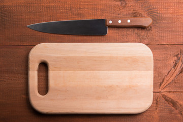 Kitchen knife and cutting board on the wooden table