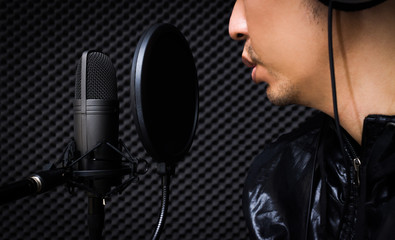 asian singer singing with condenser microphone in recording studio