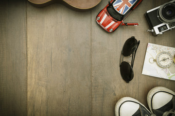 Travel accessories costumes. Passports, luggage, hat,guitar, travel maps,camera prepared for the trip place on brown wood texture,retro tone with vignette.