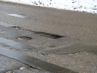 Hole in the asphalt, bad road, the risk of movement by car. Damage. Winter, Russia, 2017
