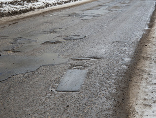 Hole in the asphalt, bad road, the risk of movement by car. Damage. Winter, Russia, 2017