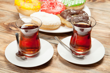 Two cups of tea and donuts on a wooden background