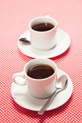Two cups of coffee on red table