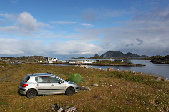 Auto und Zelt auf einer Wiese an einer Bucht mit Inselchen, im Hintergrund Gjesvaer und die Insel Storstappen in der Nähe des Nordkapp. Mageroya, Norwegen – Camping als Jedermannsrecht