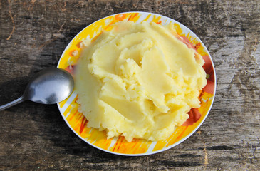 Mashed potatoes in a plate on rustic wooden table