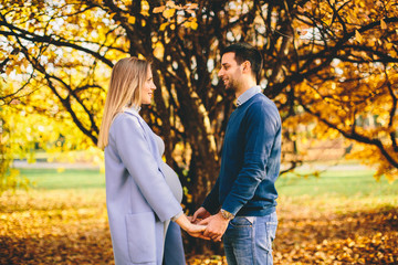 Fototapeta premium Pregnant woman and man relaxing in the autumn park