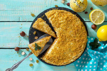 Sweet home layered honey cake on a wooden table with raisins and nuts. Top view, copy space.