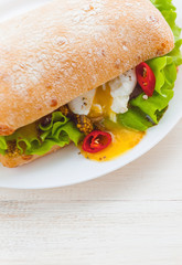 breakfast in a rustic style on a white wooden surface. ciabatta with poached egg and grain mustard with a hot cup of coffee and fresh