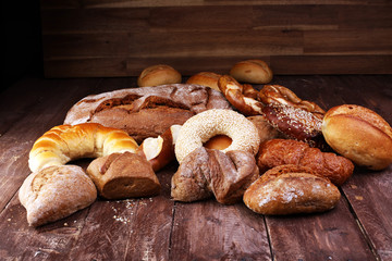 Different kinds of bread and bread rolls on board from above. Kitchen or bakery poster design.
