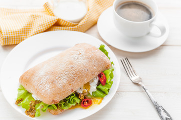 breakfast in a rustic style on a white wooden surface. ciabatta with poached egg and grain mustard with a hot cup of coffee and fresh