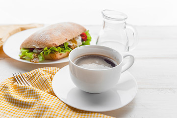 breakfast in a rustic style on a white wooden surface. ciabatta with poached egg and grain mustard with a hot cup of coffee and fresh