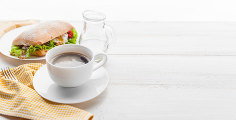breakfast in a rustic style on a white wooden surface. ciabatta with poached egg and grain mustard with a hot cup of coffee and fresh