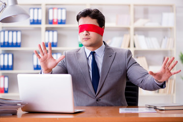 Blindfold businessman sitting at desk in office