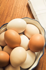 vintage rustic bowl filled with white and brown raw eggs from top view