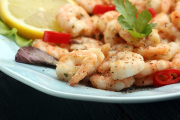 fresh shrimps served on a plate with garlic onion, lemon and chili