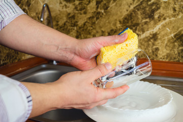 Man hands, washing a sponge with foam the dishes at the kitchen.