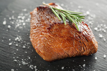 grilled steak with rosemary and pepper on dark stone