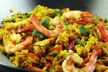 Udon stir-fry rice with shrimp and vegetables in wok pan on black burned stone background