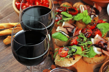 Italian antipasti wine snacks set. Cheese variety, Mediterranean olives, pickles, Prosciutto di Parma, tomatoes, artichokes and wine in glasses