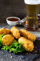 Spicy Fried Breaded chicken wings and a glass of beer on a wooden table.