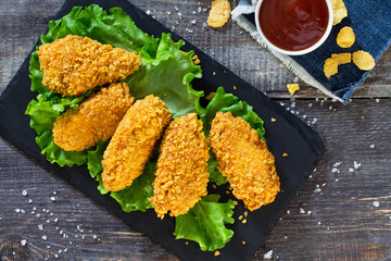 Spicy Fried Breaded chicken wings and fresh lettuce on a wooden table.