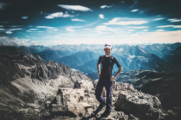 Smiling sporty man standing on an alpine summit