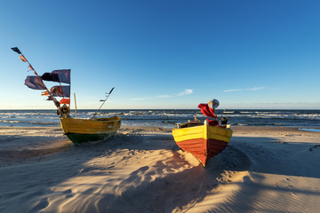 Fishing boats on sandy beach in sunset light. Baltic sea, Poland.