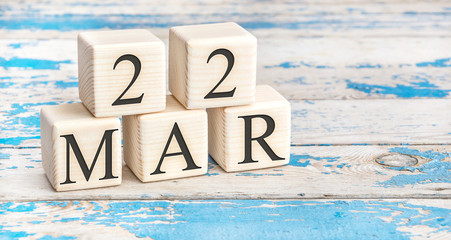 March 22nd. Wooden cubes with date of 22 March on old blue wooden background.