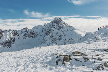 Gorgeous winter mountain landscape with group of hikers climbing on the top