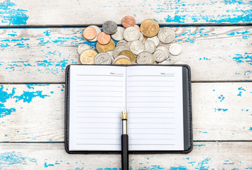 Notepad wit pen and coins on the table. Top view.