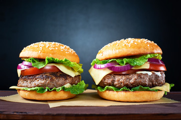 Two craft beef burgers on wooden table isolated on black  background.