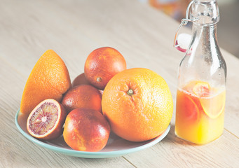 bottle with a fresh juice from the oranges and blood oranges on a wooden surface